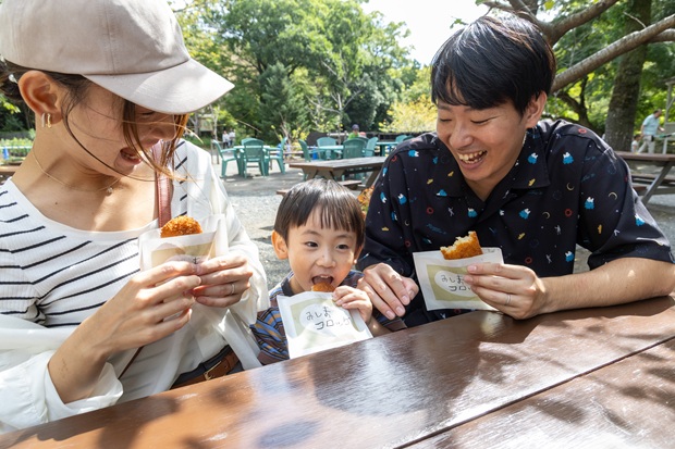 コロッケを食べる親子三人の写真